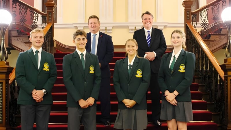 Eine Gruppe Schüler und zwei Erwachsene stehen auf der großen Treppe der Kenmore State High School.