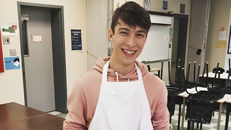 Ein Schüler der Kensington Intermediate Senior High School steht lächelnd in einem Klassenraum mit verschiedenen Geräten im Hintergrund.