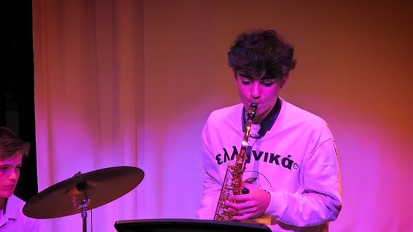 Eine Person spielt Saxophon auf der Bühne vor farbiger Beleuchtung auf der Kensington Park School.