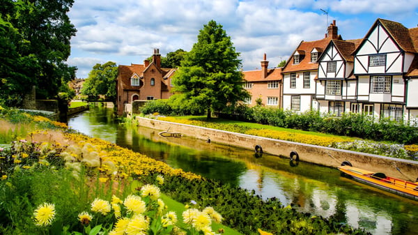 Ein Kanal mit bunten Blumen und historischen Gebäuden auf dem Gelände des Kent College.
