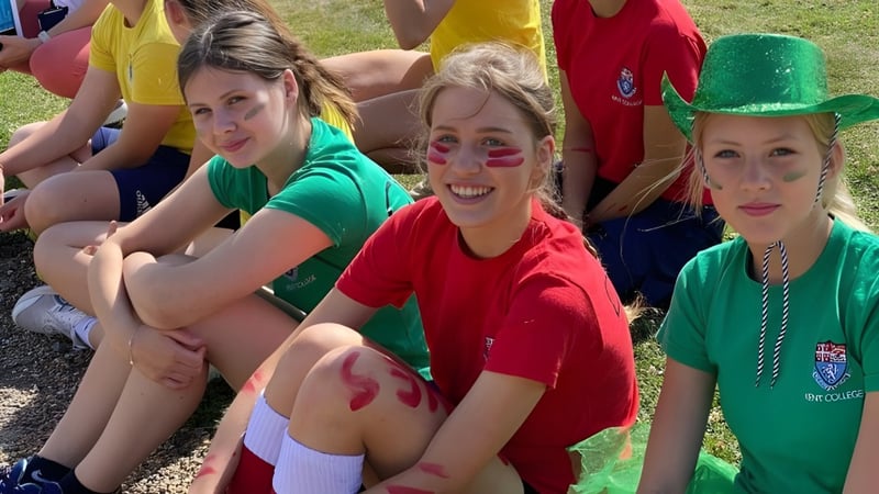 Eine Gruppe Schülerinnen sitzt auf dem Gras im Außenbereich des Kent College Pembury.