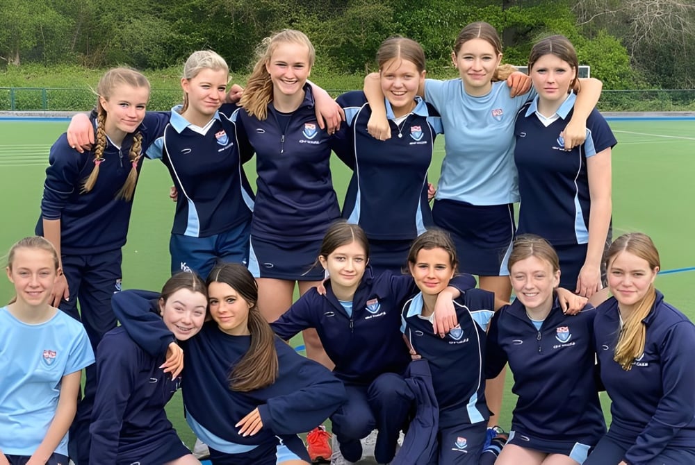 Eine Gruppe junger Sportlerinnen versammelt sich auf dem Sportplatz der Kent College Pembury.