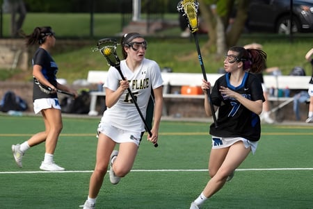 Zwei Spielerinnen der Kent Place School treten auf dem Spielfeld in einem Lacrosse-Spiel gegeneinander an.