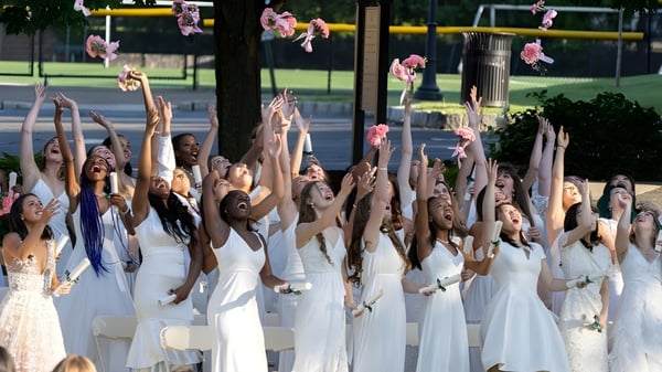 Eine Gruppe von Schülerinnen der Kent Place School führt im Freien eine synchronisierte Tanzaufführung vor grünem Hintergrund auf.