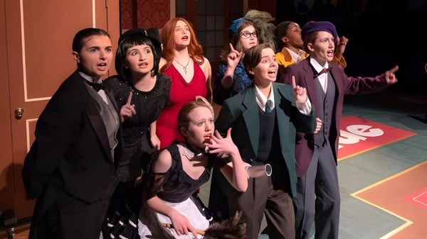 Eine Gruppe von Schülerinnen und Schülern der Kent Place School versammelt sich in einem Theater mit buntem gemustertem Boden und Wänden.