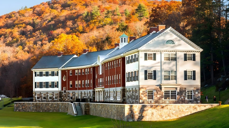Das historische Gebäude der Kent School ist von einer herbstlichen Landschaft mit bunten Laubbäumen und einem grünen Rasen umgeben.