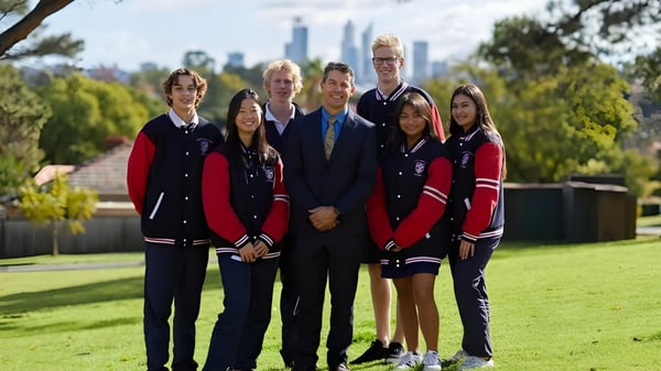 Eine Gruppe von Schülerinnen und Schülern der Kent Street Senior High School posiert vor der Stadtkulisse mit hohen Gebäuden.