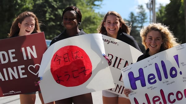 Schülerinnen der Kents Hill School halten in einem Park Schilder mit verschiedenen Botschaften.