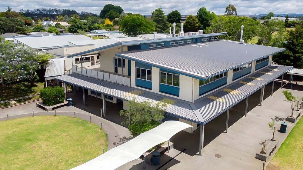 Das moderne Gebäude der Kerikeri High School steht eingebettet in eine grüne Landschaft mit Bäumen und Vegetation.