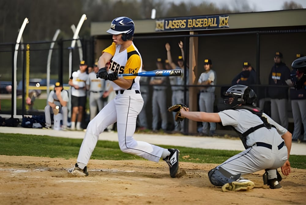 Ein Baseballspieler der Kettle Moraine High School steht am Schlagmal auf dem Baseballfeld mit einem Fangspieler dahinter.