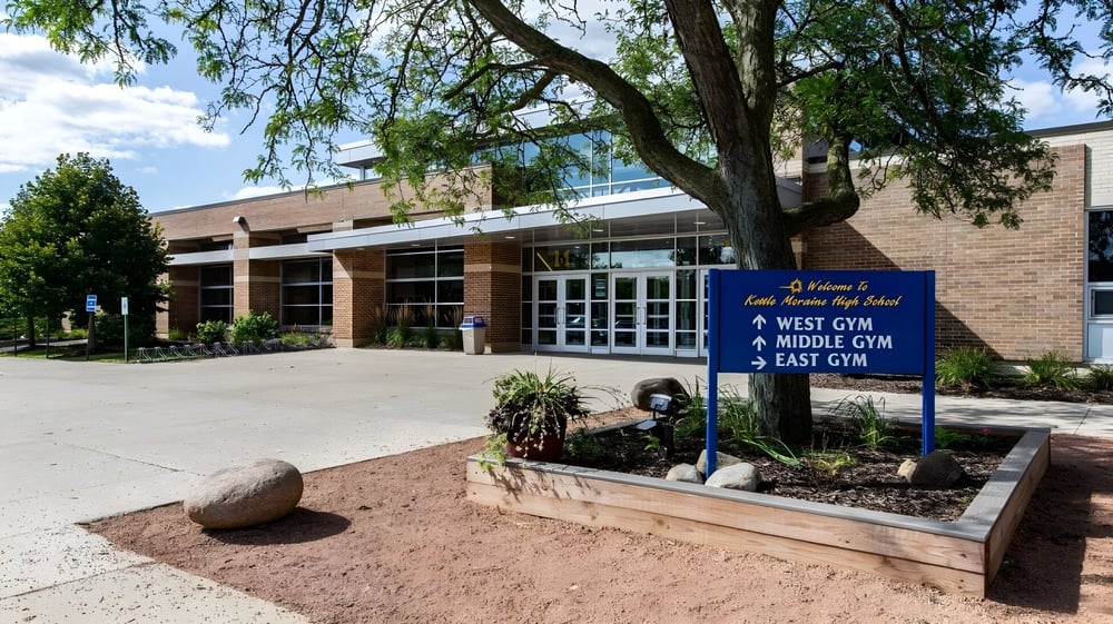 Das Ziegelgebäude mit Hinweisschildern zu verschiedenen Sporthallen auf dem Gelände der Kettle Moraine High School.