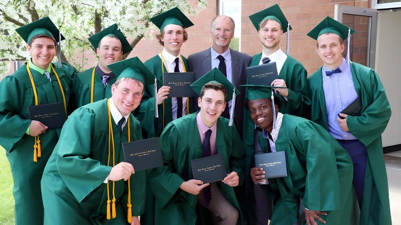 Absolventinnen und Absolventen der Kettle Moraine High School stehen in grünen Talaren vor einem Backsteingebäude und halten ihre Diplome.