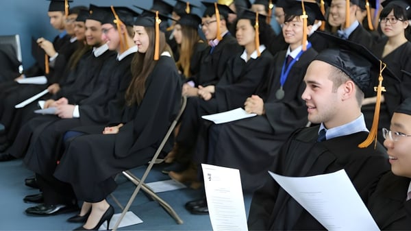 Absolventinnen und Absolventen der Keystone School sitzen in Reihen in ihren Abschlussgewändern und schauen in die Kamera.