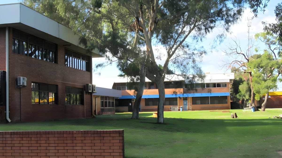 Das moderne Backsteingebäude mit farbigen Akzenten auf dem Campus des Kiara College ist von einer grünen Rasenfläche und Bäumen umgeben.