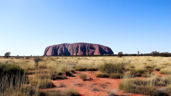 Weite, trockene Landschaft mit einer hohen Felsformation und einem roten Weg auf dem Gelände des Kiara College.