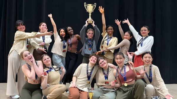 Schülerinnen von Kildonan East Collegiate feiern auf der Bühne und halten einen Pokal bei der Siegerehrung.