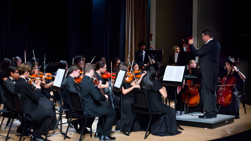 Das Symphonieorchester der Kilkenny City Vocational School führt ein Konzert mit Musikern und einem Dirigenten auf der Bühne auf.
