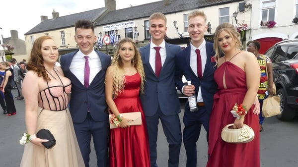 Eine Gruppe von Personen in formeller Kleidung posiert vor dem Stadtbild auf dem Campus des Kilkenny College.