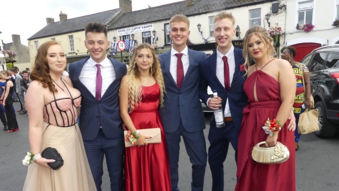 Eine Gruppe gut gekleideter Personen posiert gemeinsam vor einem Gebäude auf dem Campus des Kilkenny College.