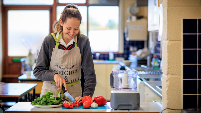 Eine Schülerin des Kilkenny College bereitet in der Schulküche frisches Gemüse zu.