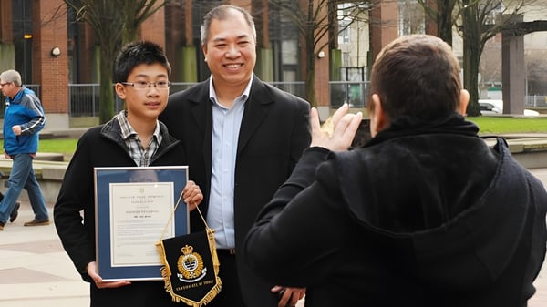 Ein Schüler der Killarney Secondary School erhält im Freien eine Auszeichnung von einem älteren Mann.