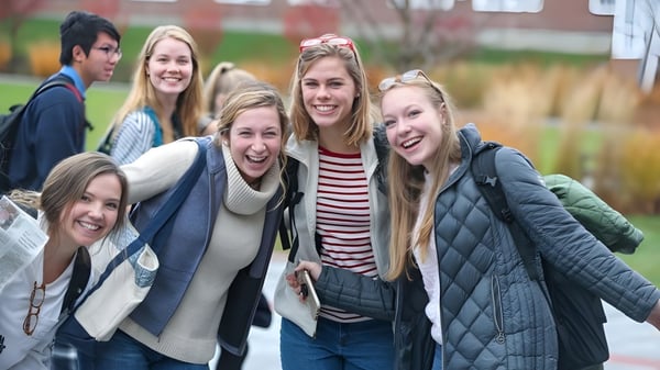 Eine Gruppe lächelnder Schülerinnen und Schüler der Kimball Union Academy steht im Winter draußen vor Backsteingebäuden.