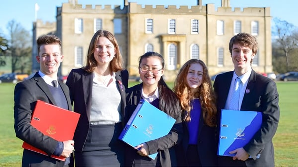 Fünf junge Erwachsene stehen in formeller Kleidung vor einem historischen Gebäude auf dem Gelände der Kimbolton School.