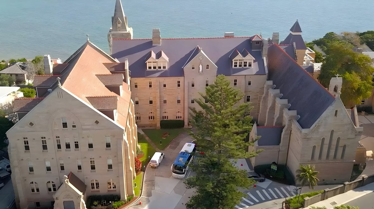 Das Schloss mit mittelalterlicher Architektur auf dem Gelände von Kincoppal-Rose Bay ist von grünen Bäumen umgeben.