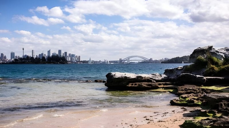 Blick auf das Küstenpanorama mit Felsen und Wasser vor der Skyline von Sydney auf dem Campus der Kincoppal-Rose Bay.