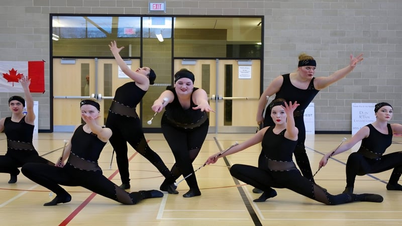Eine Tanzgruppe der King City Secondary School führt eine synchronisierte Choreografie vor einer Backsteinwand im Innenraum auf.