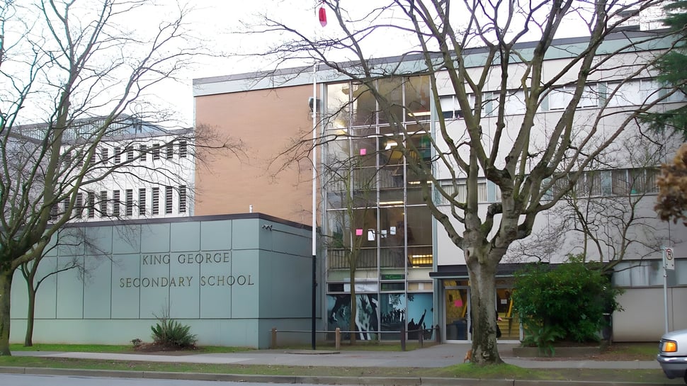 Das Backsteingebäude der King George Secondary School ist mit kahlen Bäumen im Vordergrund zu sehen.