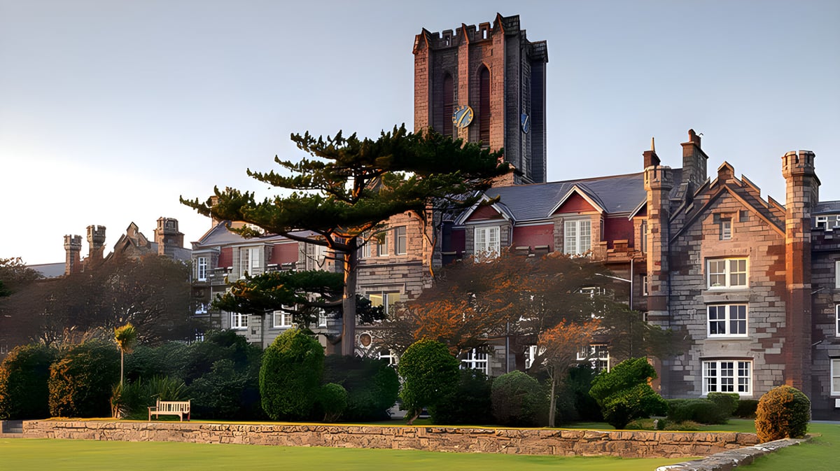 Das King William's College zeigt ein schlossähnliches Gebäude mit hohen Türmen und verzierter Architektur vor klarem Himmel.