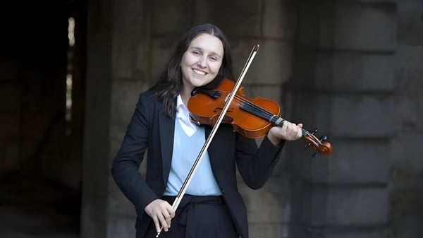 Eine Person spielt auf dem Campus des King William's College Geige vor dunklem Hintergrund.