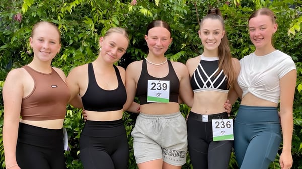 Eine Gruppe von fünf Schülerinnen in Sportkleidung steht im grünen Außenbereich der Kingaroy State High School.