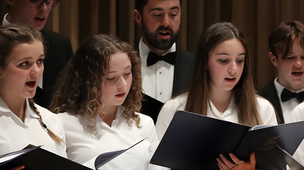 Eine Gruppe Schülerinnen und Schüler des King's Bruton singt gemeinsam bei einem Auftritt auf der Bühne.