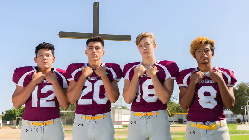 Vier Schüler der Kings Christian School stehen vor einem großen Kreuz im Freien.