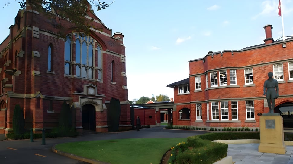 Das Backsteingebäude mit Rundbogenfenstern und ein grüner Hof sind auf dem Campus des King's College zu sehen.