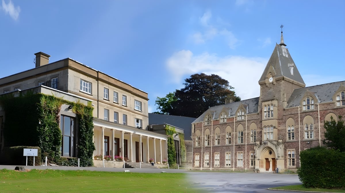 Das historische Gebäude mit hoher Spitze auf dem Gelände des King's College ist von grünen Bäumen umgeben.