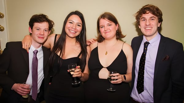 Vier Personen stehen zusammen bei einer Veranstaltung am King's College und tragen formelle Kleidung.