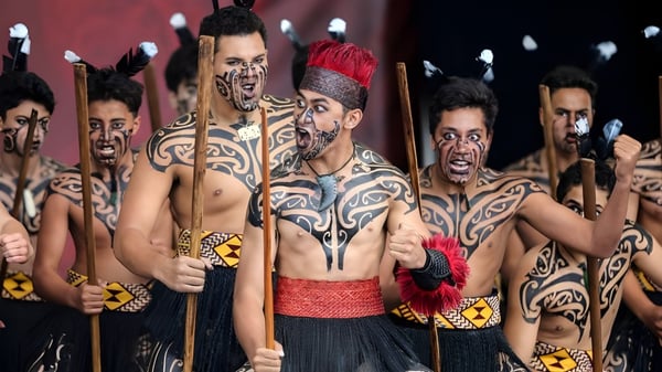 Eine Gruppe mit komplexen Körperbemalungen und traditioneller Kleidung bei einer Kunstperformance am King's College.