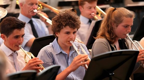 Schüler des King's College spielen auf einer Bühne verschiedene Musikinstrumente während einer Aufführung.