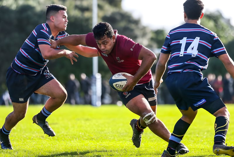 Drei Rugbyspieler absolvieren einen intensiven Tackling-Moment auf einem Spielfeld der King's College.
