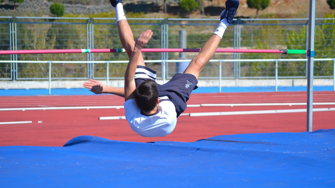 Eine Schülerin führt einen Stabhochsprung auf der Sportanlage des King's College aus.