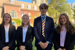 Vier Schülerinnen und Schüler stehen gemeinsam vor einem historischen Backsteingebäude auf dem Campus der King's Ely.