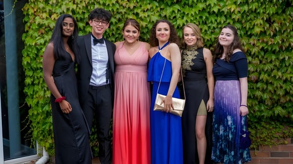 Eine Gruppe von fünf Personen in formeller Kleidung steht vor einer mit Efeu bewachsenen Wand auf dem Gelände der King's School.