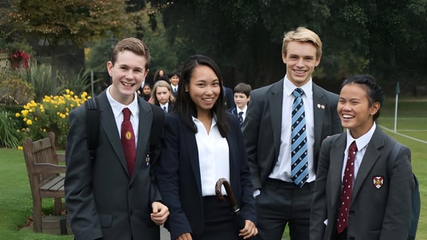 Eine Gruppe Schüler in formeller Kleidung steht gemeinsam in einem Garten auf dem Gelände der King's School Rochester.