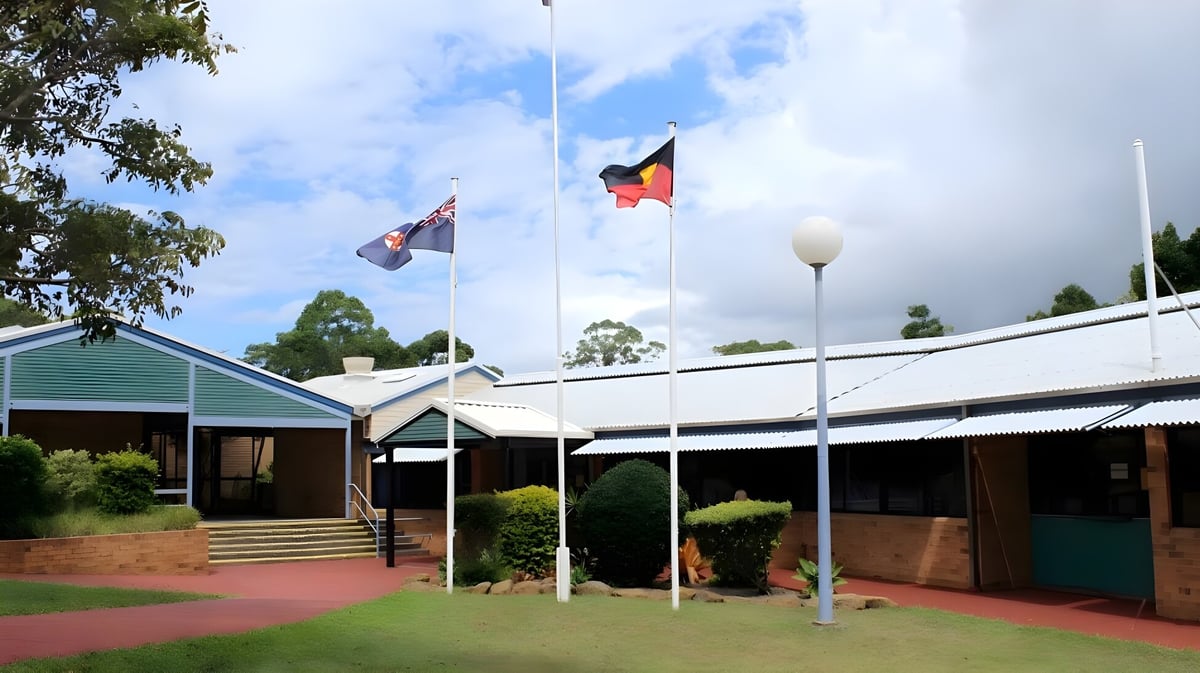 Das Gebäude der Kingscliff High School ist umgeben von dichter Vegetation und zeigt die australische Flagge sowie eine weitere Flagge.