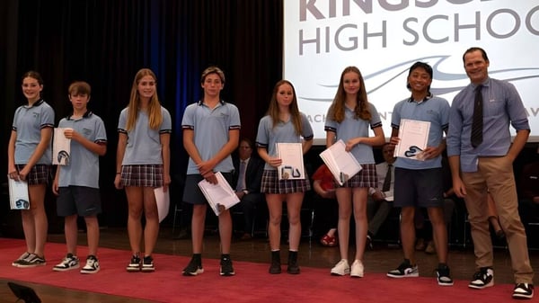 Eine Gruppe von Schülerinnen und Schülern steht auf der Bühne der Kingscliff High School und hält Zertifikate oder Auszeichnungen.