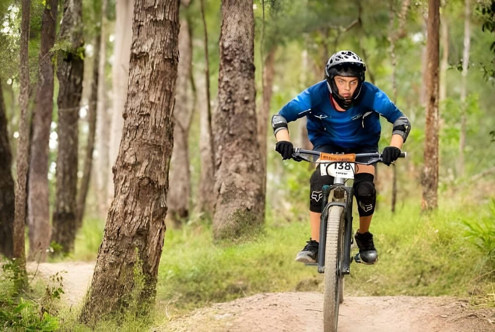 Ein Schüler der Kingscliff High School fährt mit einem Mountainbike auf einem Waldweg.