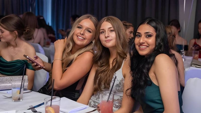 Eine Gruppe Schülerinnen der Kingsley School posiert bei einer formellen Veranstaltung vor einem Vorhang.